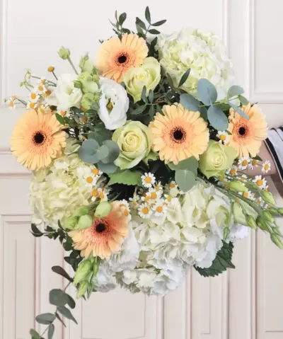 Bouquet de flores amarelas, brancas e verdes com parede branca ao fundo