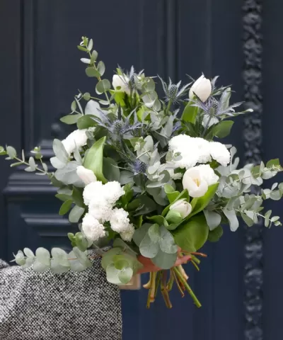 Ramo de flores brancas e verdes com fundo azul e cadeira cinzenta