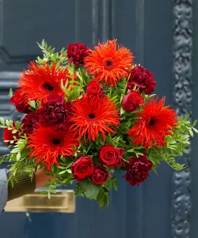 Bouquet colorido de flores vermelhas e laranja com folhagem verde