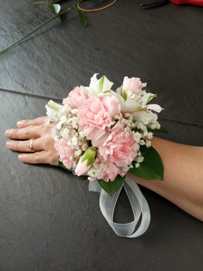 Pulseira de flores com cravos cor-de-rosa e folhas verdes no pulso
