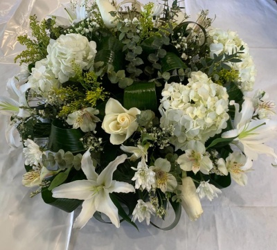 Arranjo floral com flores brancas e folhas verdes sobre tecido branco