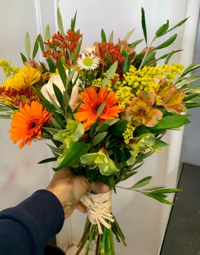 Ramo de flores coloridas com talos amarrados e mão segurando