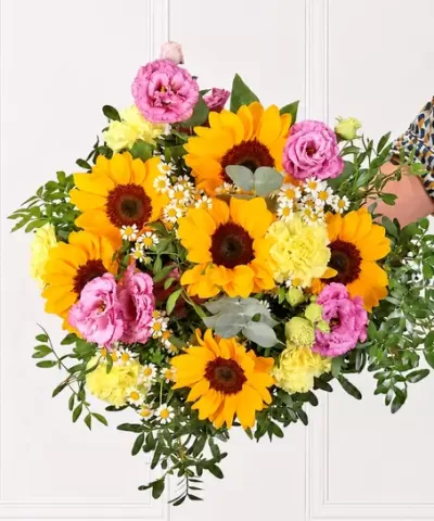 Bouquet floreal com girassóis amarelos, flores rosas e amarelas, folhas verdes