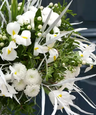 Arranjo floral branco com folhas verdes e detalhes prateados