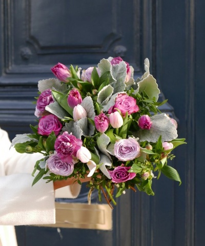 Ramo de flores com rosas e tulipas com folhagem a frente de uma porta azul escura
