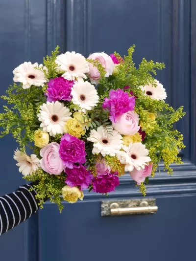 Bouquet colorido de flores variadas contra porta azul