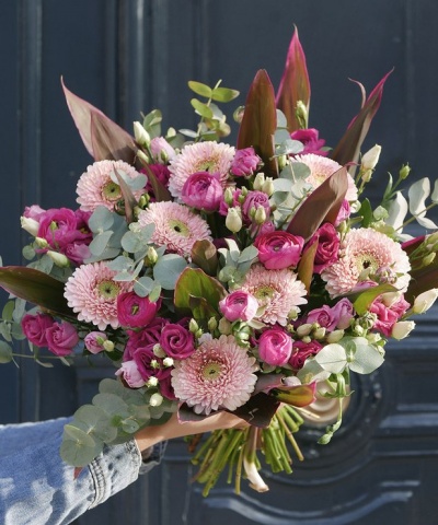 Buquê colorido de flores rosas e verdes com folhas castanhas numa mão