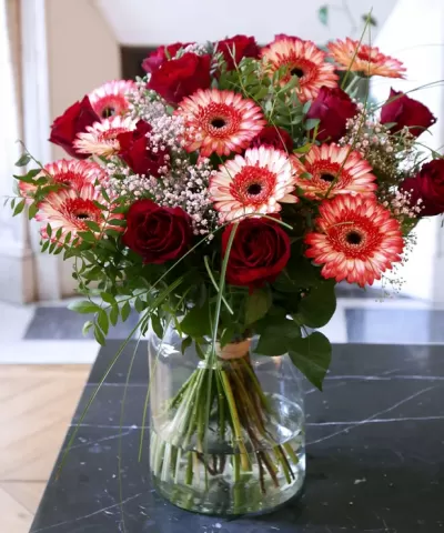 Arranjo floral com rosas vermelhas e flores gerbera em vaso de vidro