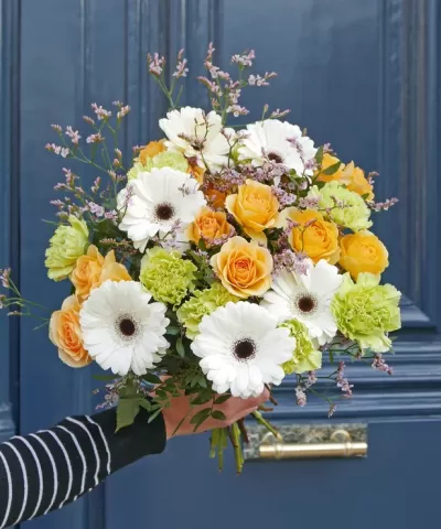 Buquê de flores coloridas tenras em frente a uma porta azul escura