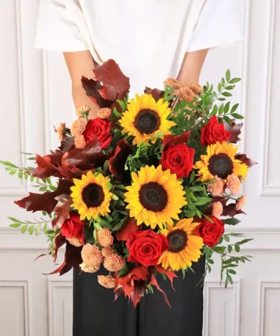 Buquê de flores com girassóis, rosas vermelhas e folhas castanhas