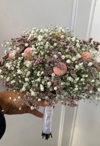 Bouquet de flores brancas, lilases e cor-de-rosa com haste envolta em fita branca satinada