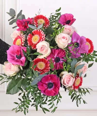 Bouquet de flores variadas com rosas, flores vermelhas, anémonas roxas e folhagem verde