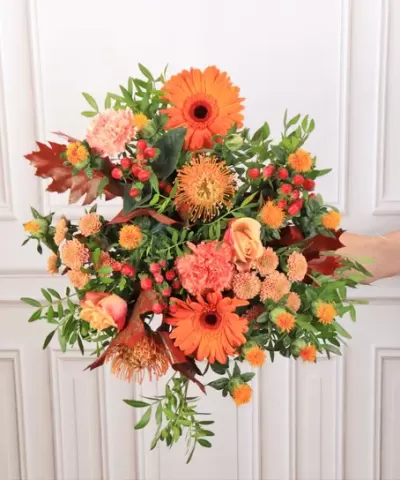 Arranjo floral laranja com várias flores e folhas verdes