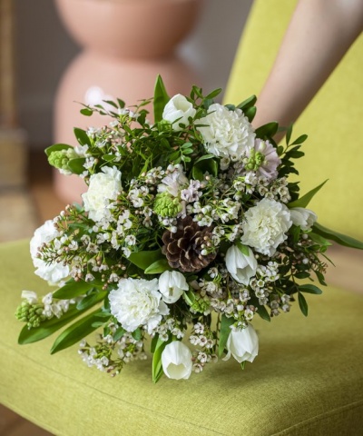 Ramo de flores brancas e verdes com pinheiro colocado sobre tecido verde limão