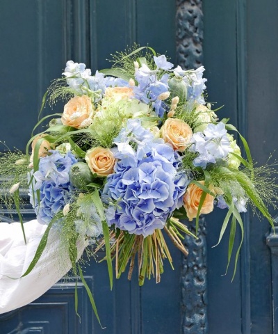 Bouquet de flores azuis, pêssego e verdes em porta azul