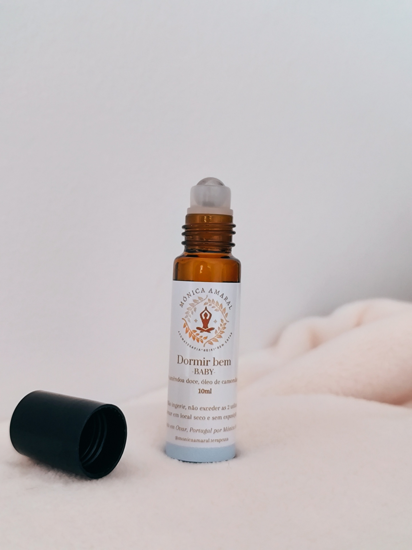 Roll on Dormir bem Frasco roll-on âmbar com tampa preta removida sobre tecido creme