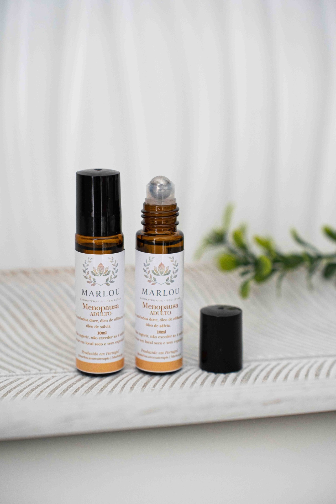 Roll on Menopausa Frascos de vidro âmbar com aplicador roll-on e rótulos com texto sobre superfície têxtil clara.