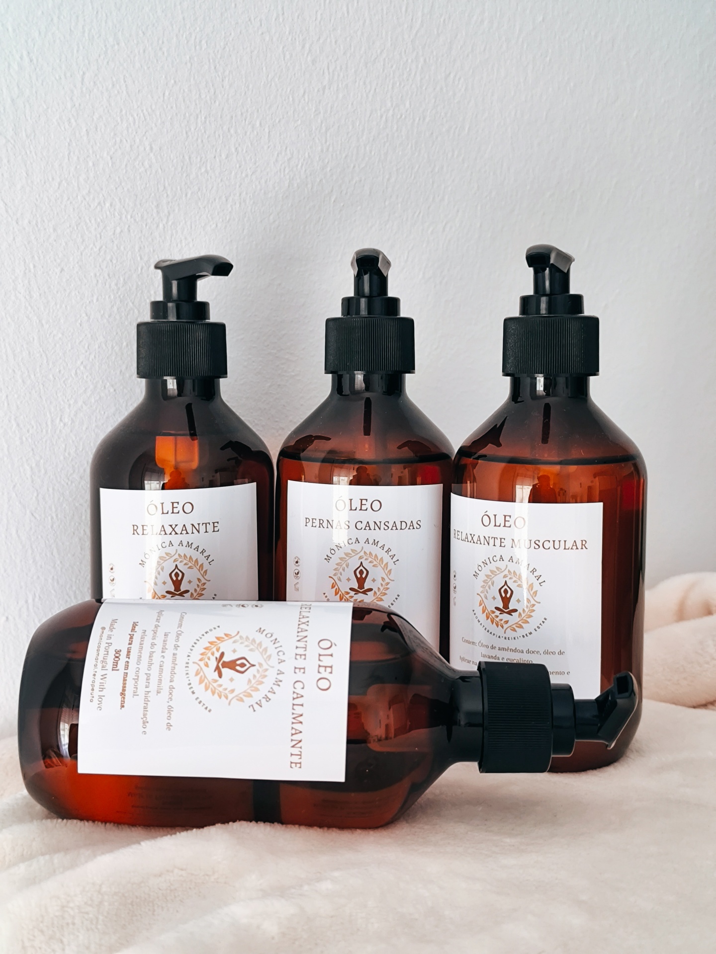 Óleo Pernas cansadas Quatro frascos âmbar com óleo relaxante com diferentes rótulos em português dispostos sobre superfície clara