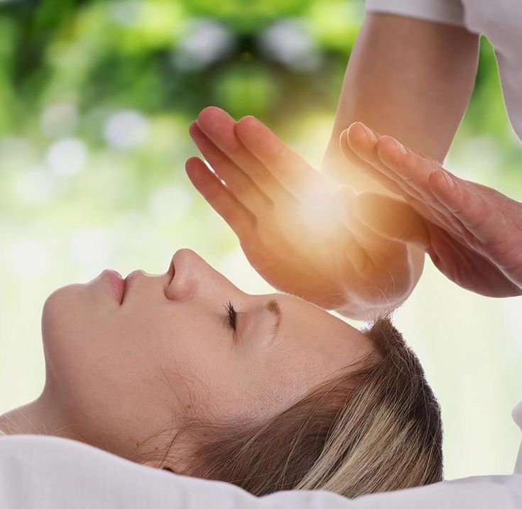 Sessão de Reiki Pessoa deitada recebendo terapia com as mãos em ambiente relaxante