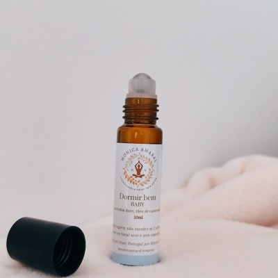 Frasco roll-on âmbar com tampa preta removida sobre tecido creme