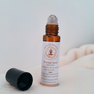 Frasco roll-on castanho com tampa preta removida e rótulo branco com texto em português.