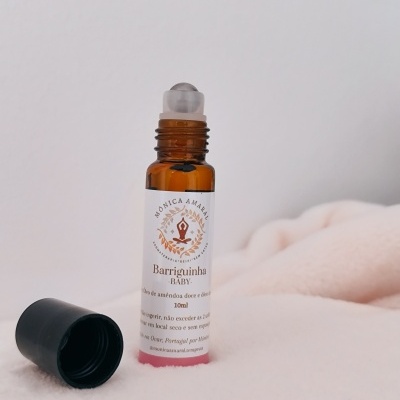 Frasco de óleo roll-on em vidro âmbar com rótulo branco e tampa preta sobre tecido claro