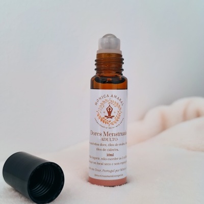 Frasco roll-on âmbar para dores menstruais com etiqueta branca e tampa preta removida sobre superfície branca