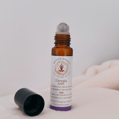 Frasco de vidro âmbar com roll-on e tampa preta ao lado sobre superfície macia clara