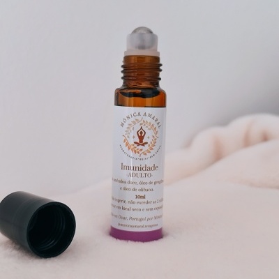 frasco de vidro castanho com rolha preta removida e rótulo branco e roxo sobre superfície creme