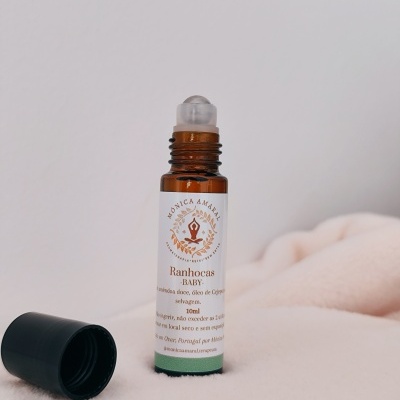 Frasco roll-on âmbar com tampa preta e etiqueta branca sobre tecido creme claro