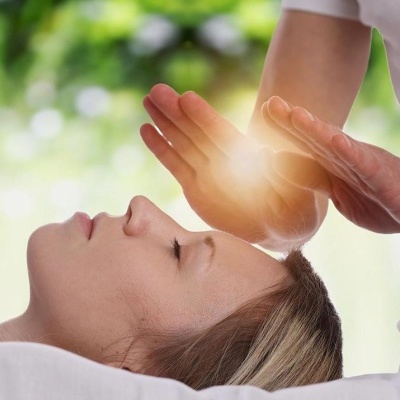 Pessoa deitada recebendo terapia com as mãos em ambiente relaxante