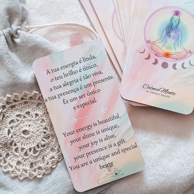 Cartas de mensagens bilingues em tons pastel sobre energia e meditação, com saco tecido cinzento e renda bege no fundo