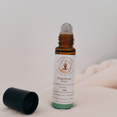 Frasco de repelente baby em vidro âmbar com rolha e tampa preta removida sobre tecido claro