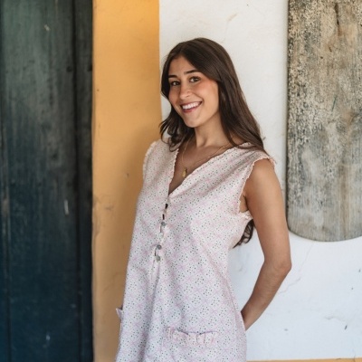 Vestido curto padrão geométrico rosa e verde com botões e bolsos em fundo de parede branca e amarela