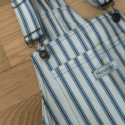 Jardineira branca com riscas azuis e etiqueta Monkiki