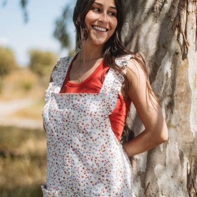 Macacão floral branco com bolsos e folhos, usado com t-shirt vermelha ao ar livre