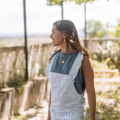 Mulher de perfil com jardineira floral e blusa jeans ao ar livre