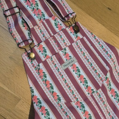 Macacão de tecido com padrão de riscas rosa e branco com flores cor-de-rosa e folhas verdes