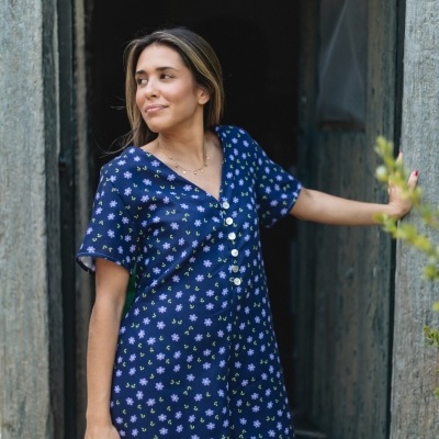 Vestido curto azul escuro com flores lilases e verdes numa porta de madeira