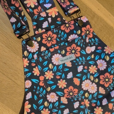 Macacão floral colorido MonKiki com alças ajustáveis sobre mesa de madeira