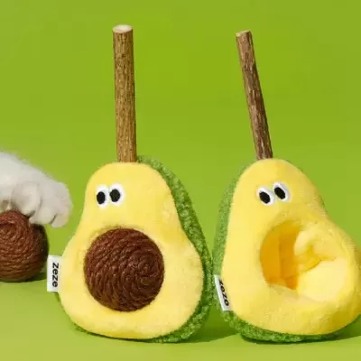 Brinquedos de peluche abacate com olhos e pau, sobre fundo verde.