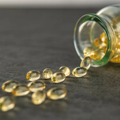 Frasco de vidro aberto com cápsulas amarelas espalhadas