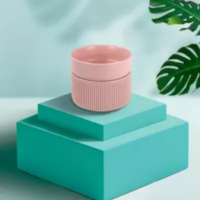 Tigelas rosadas empilhadas sobre caixas azuis com folhas verdes ao fundo