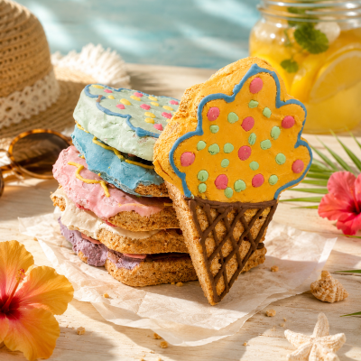 Biscoitos coloridos em forma de gelado empilhados numa mesa com decoração de verão