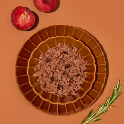 Prato castanho com carne picada, dois pêssegos cortados e ramo de alecrim