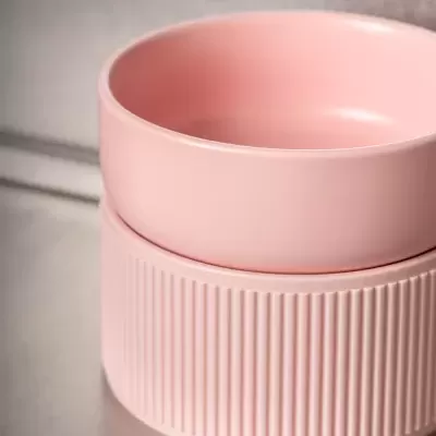 Conjunto de duas taças cor-de-rosa em cerâmica, uma lisa e uma texturizada, sobre superfície metálica