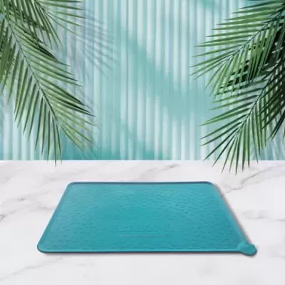 Tapete azul com textura de bolinhas colocado em superfície branca com padrão mármore e fundo azul com sombras de folhas de palmeira
