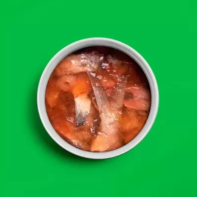 Tigela branca com carne em gelatina sobre fundo verde