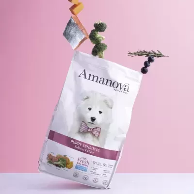 Saco branco de ração para cães Amanova Puppy Sensitive com imagem de cachorro e elementos flutuantes