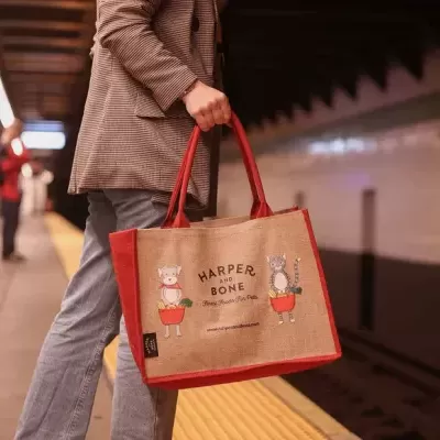 Saco de compras em juta com alças vermelhas e estampas de cão e gato em estação de metro